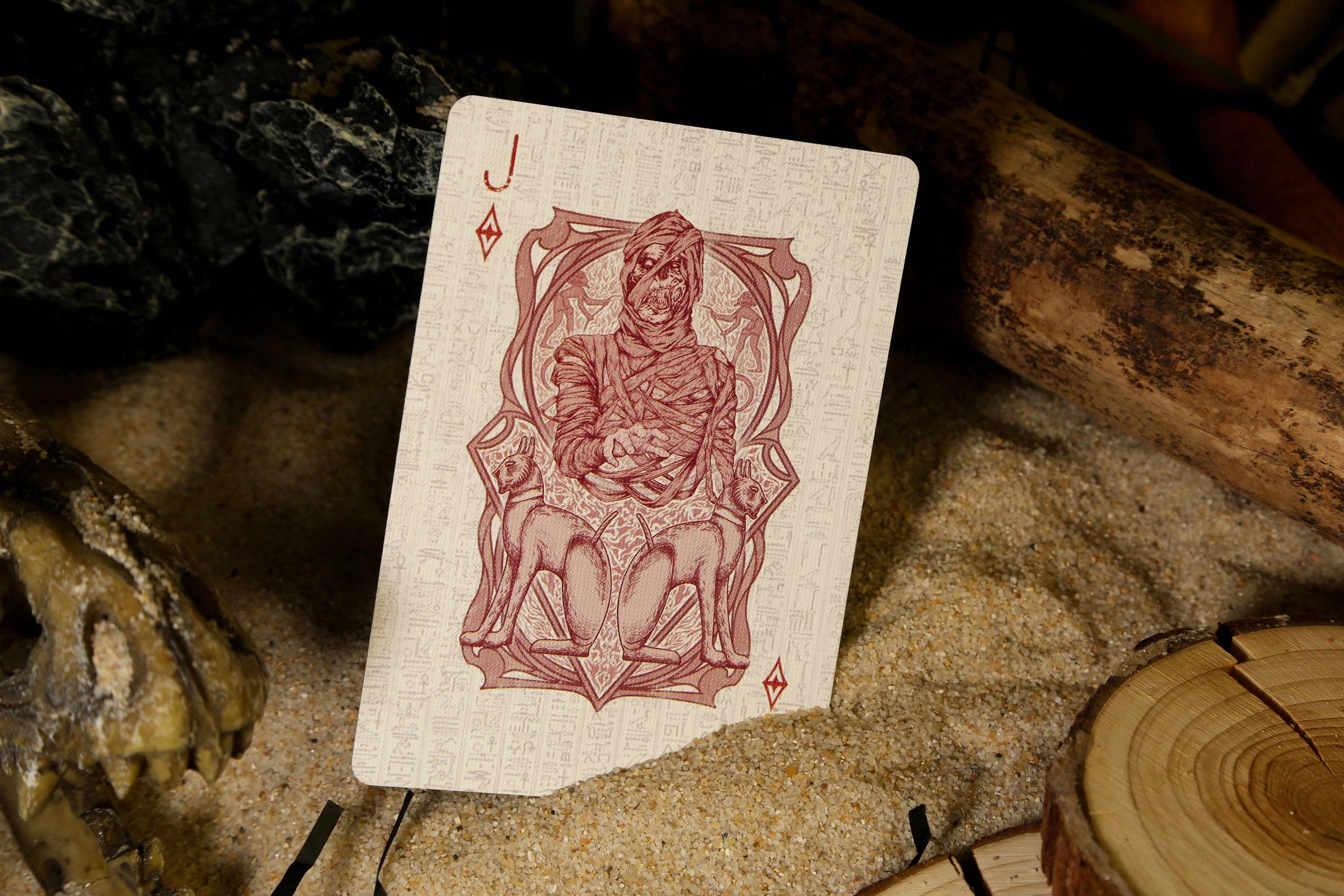 Jack of Diamonds playing card on a rustic background with rocks and wood.