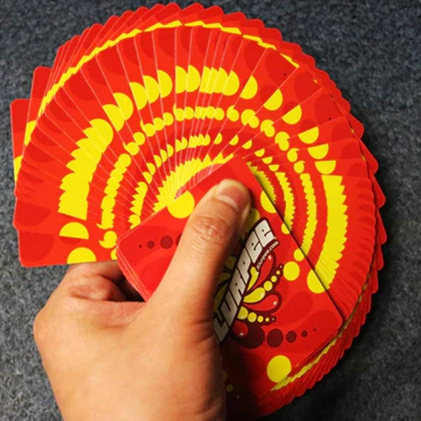 Hand holding a deck of red Slurpee playing cards with yellow designs on a dark gray background