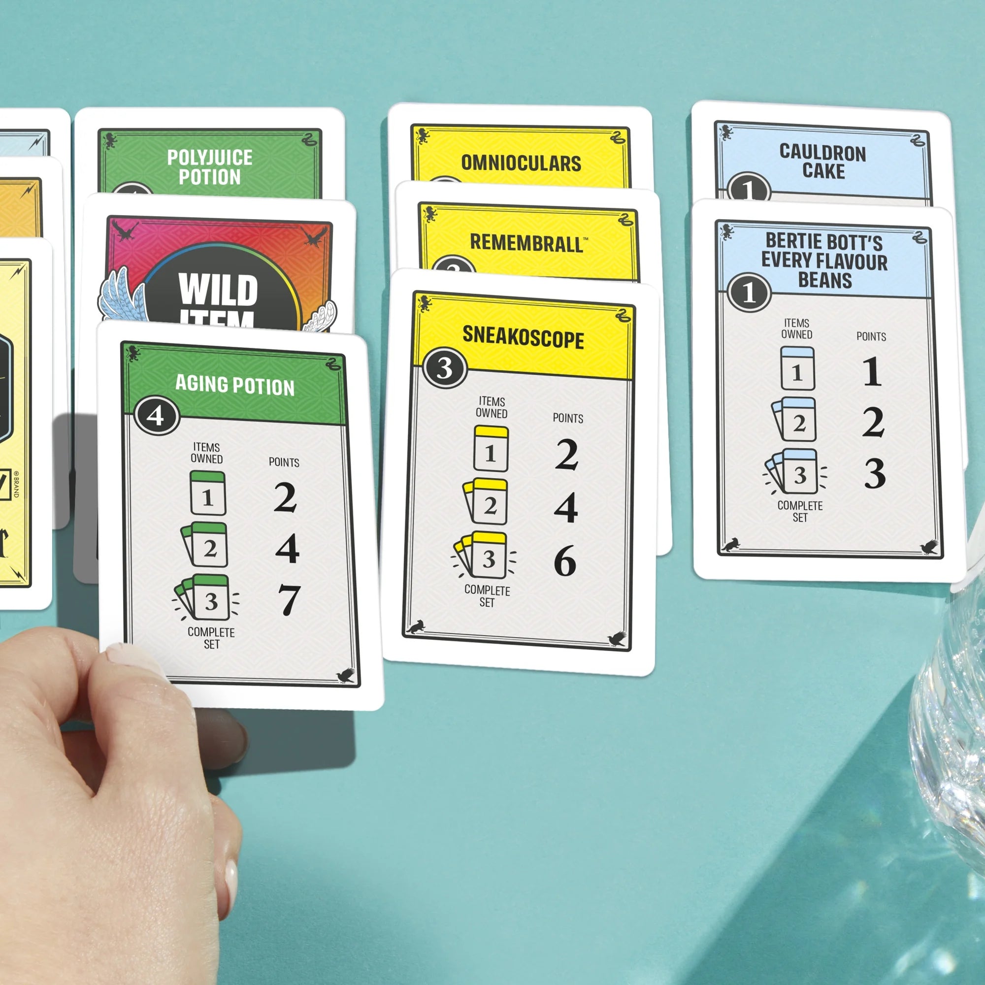 Collection of Monopoly Deal Harry Potter game cards with various text and graphics on a teal background