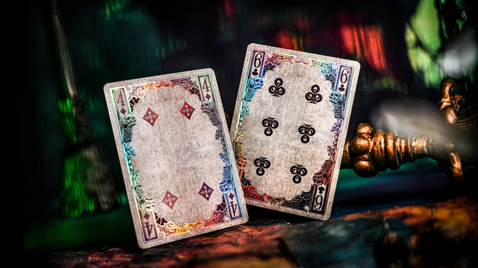 Two playing cards, one with a red diamond symbol and the other with black clover symbols, on a dark background.