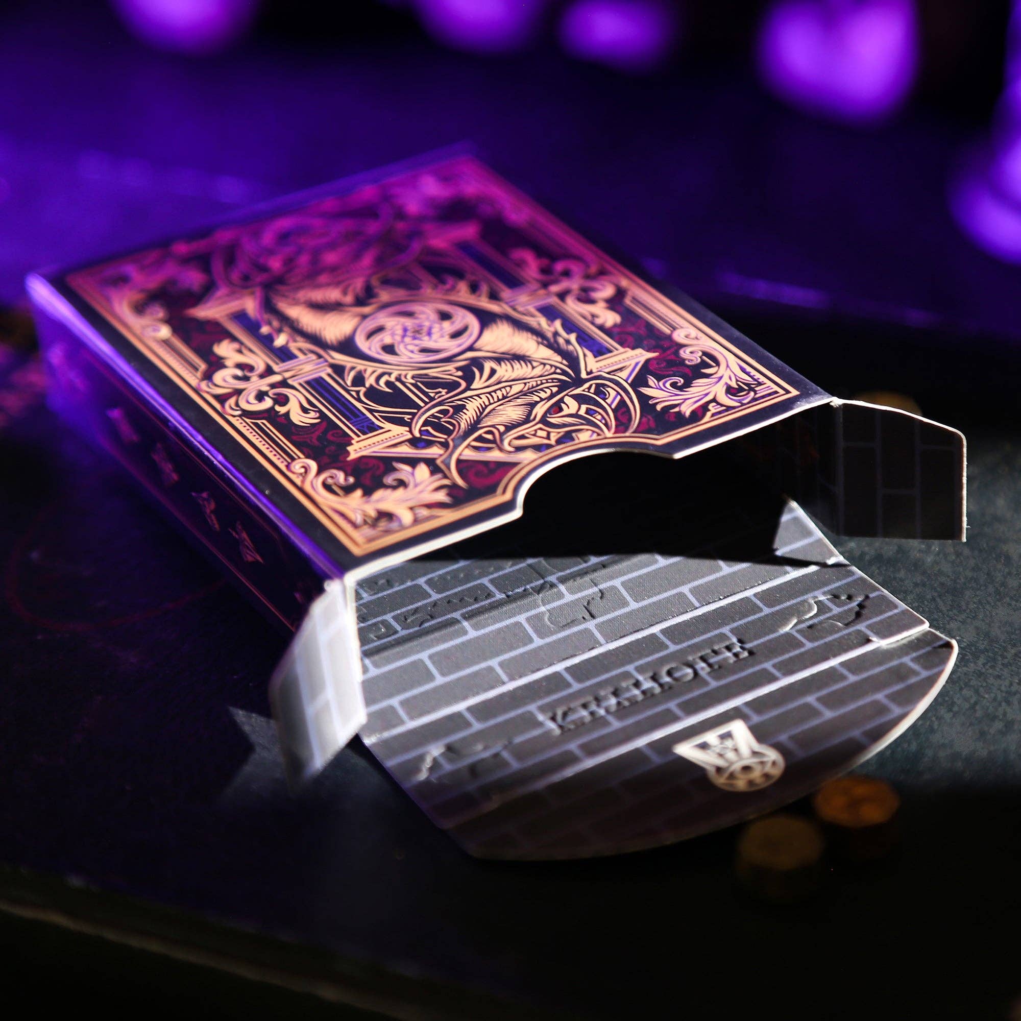 Playing cards with a purple and gold deck cover on a dark background