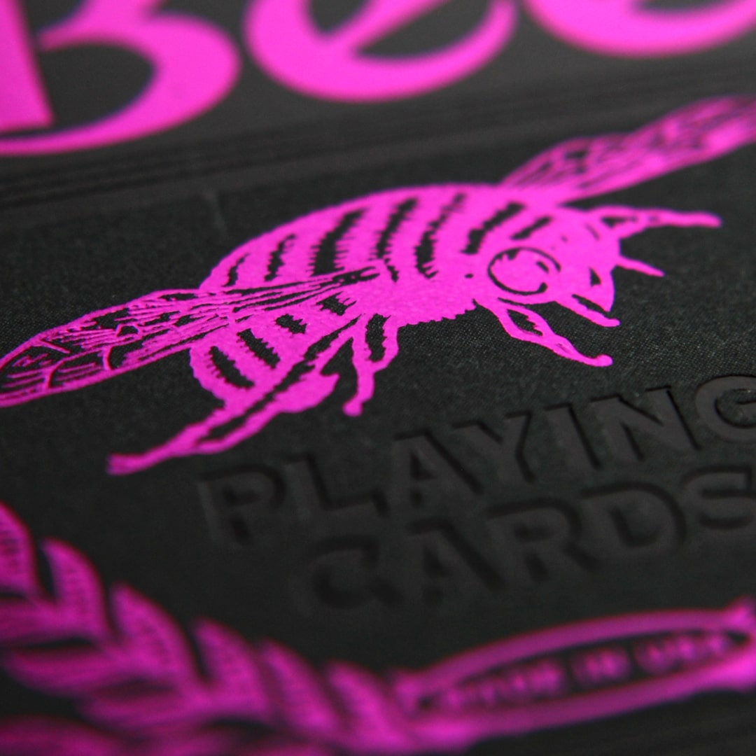 Close-up of a Bee Magenta & Black Metalluxe playing card with pink bee design on black background