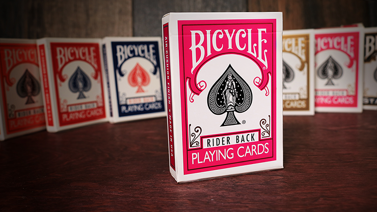 Bicycle playing cards with a fuchsia and white design on a wooden surface.