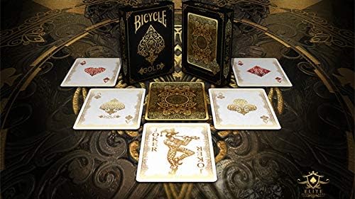 Display of Bicycle Gold deck tuck box surrounded by Aces and Joker cards with ornate gold designs on a dark patterned table.”