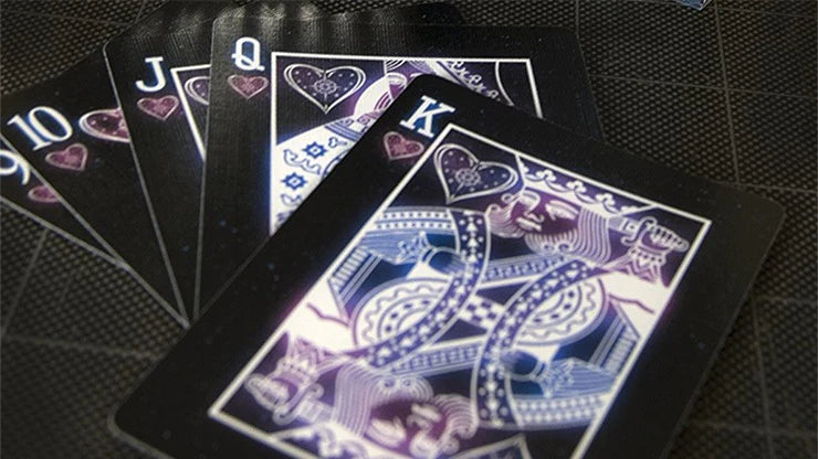 Black playing cards with blue and purple designs on a dark surface