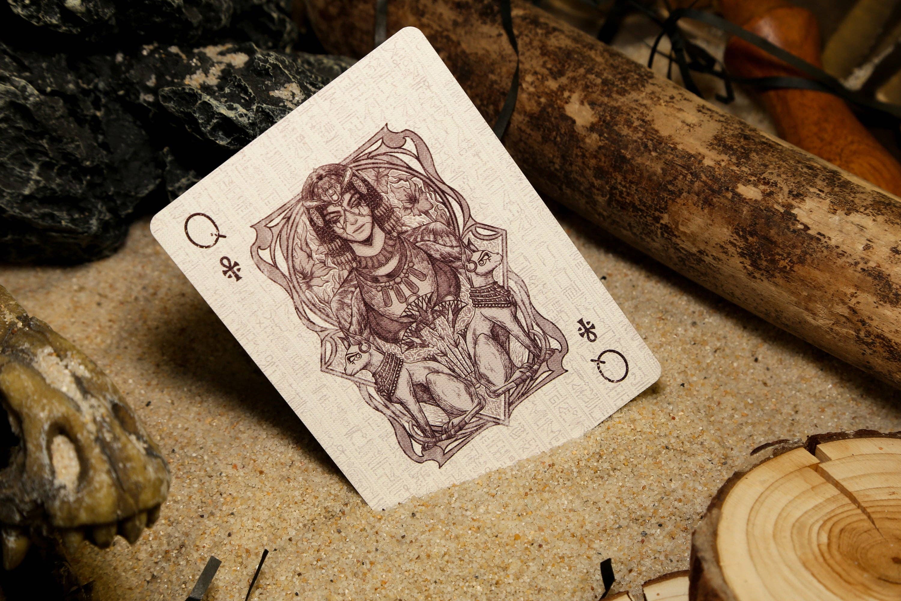 Playing card with a Queen of Clubs design on a rustic background with bones and wood.