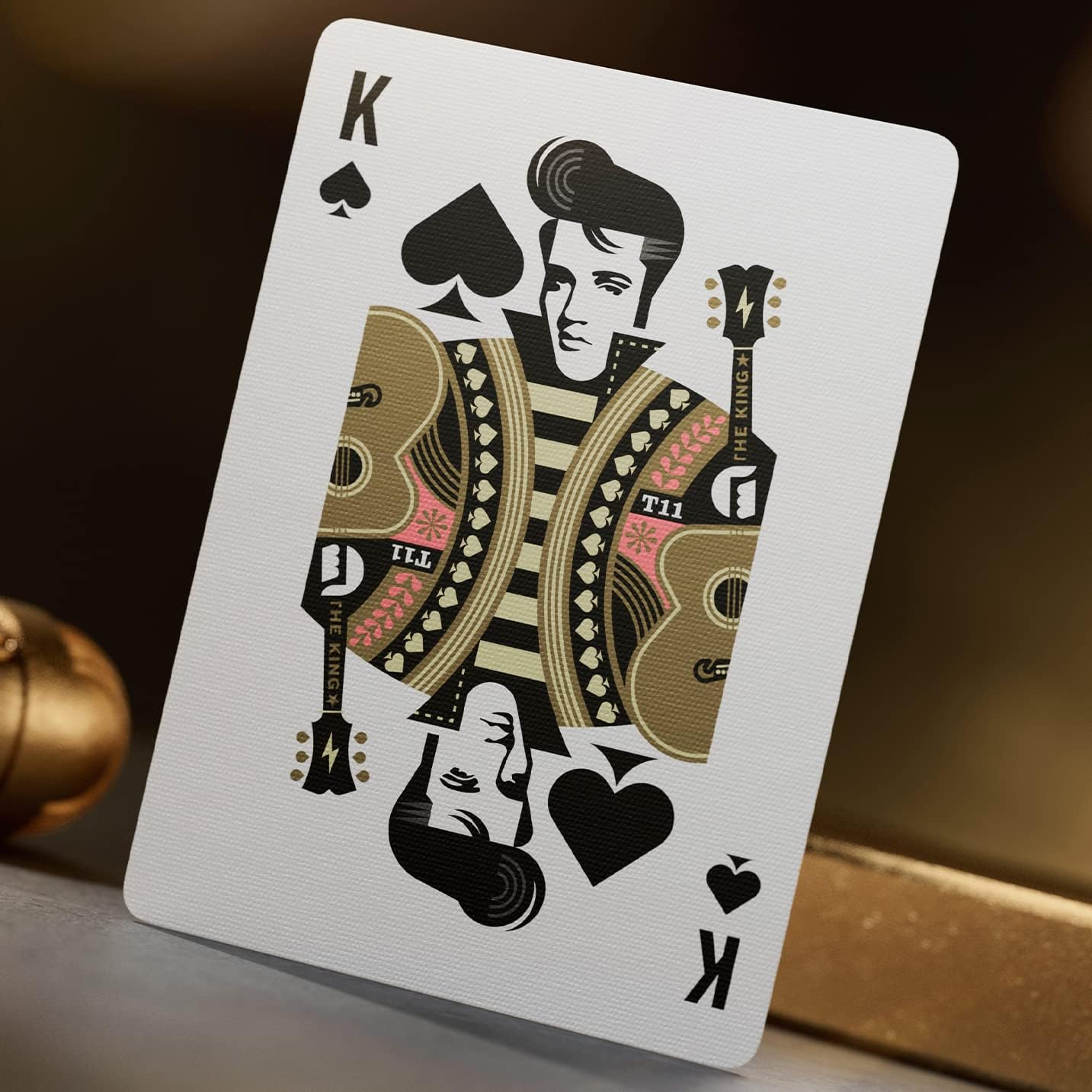 King of spades from Theory11 Elvis deck showing stylized Elvis portrait with guitars and gold accents.