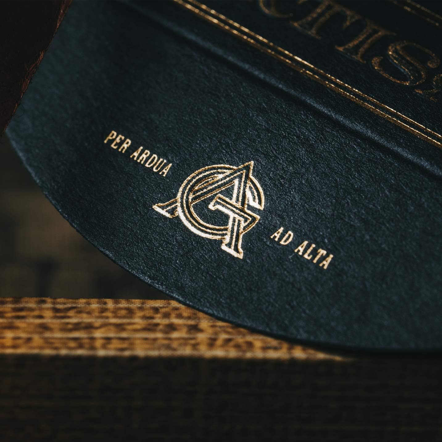 Close-up of a dark green leather product with gold embroidery on a wooden surface