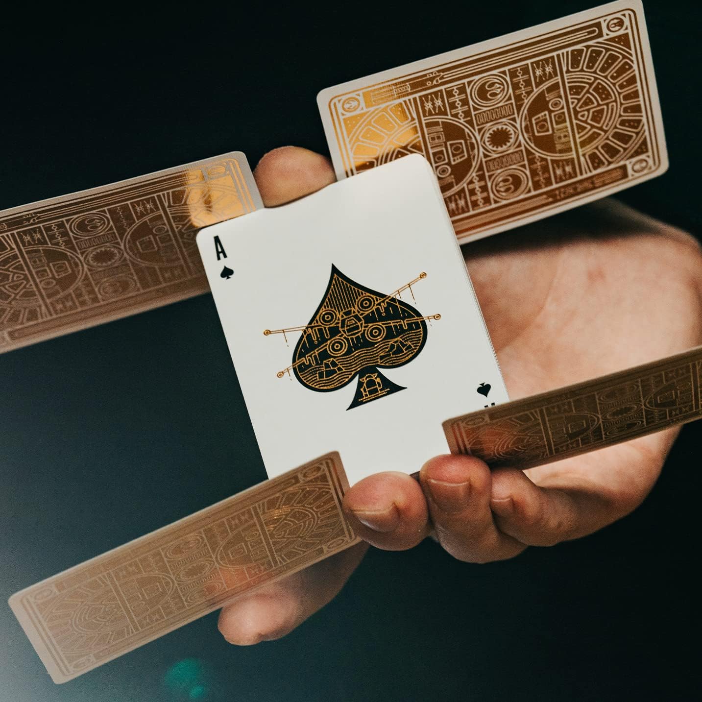 Hand holding a playing card with an ace of spades design on a dark background