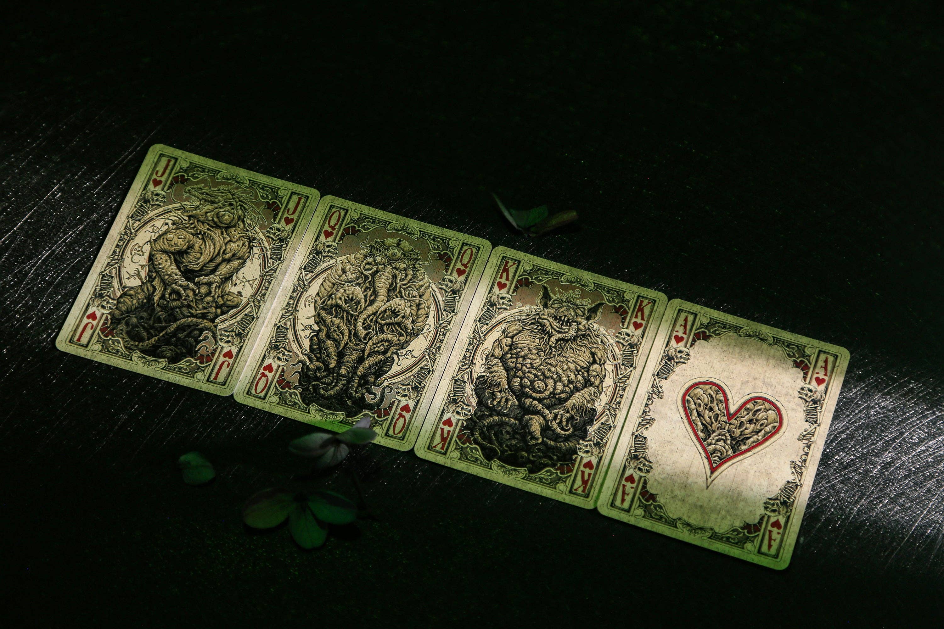 Four playing cards with intricate designs on a dark surface