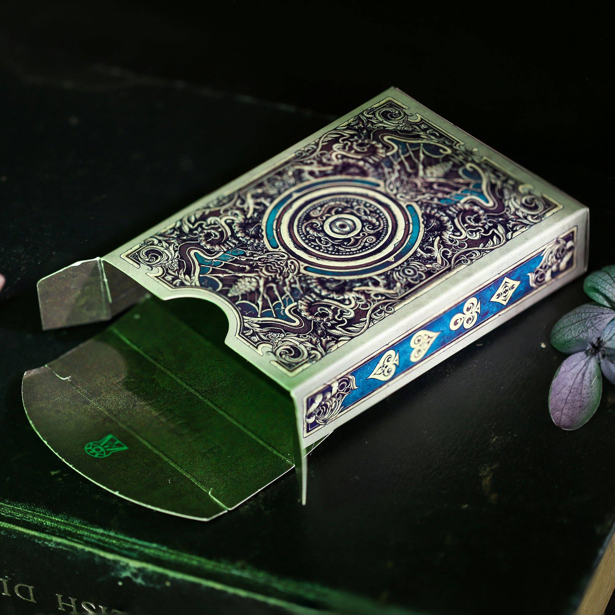 Decorative playing card box with intricate design on a dark surface