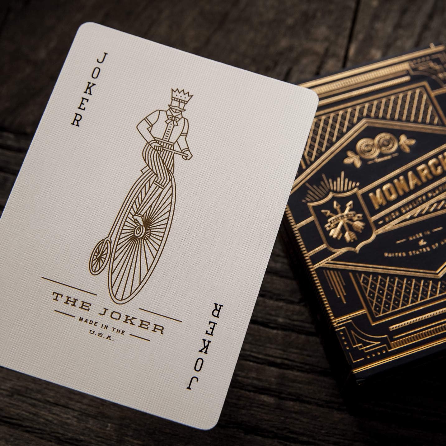 Playing card featuring 'The Joker' design on a wooden surface with Monarch Playing Cards packaging.