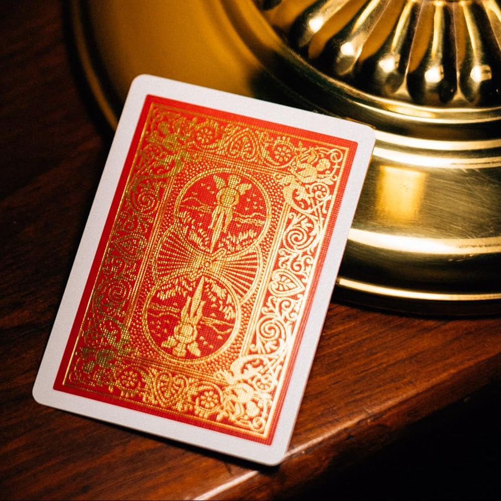 Red Bicycle 140th Anniversary playing card with gold design on a wooden surface with a green lamp in the background