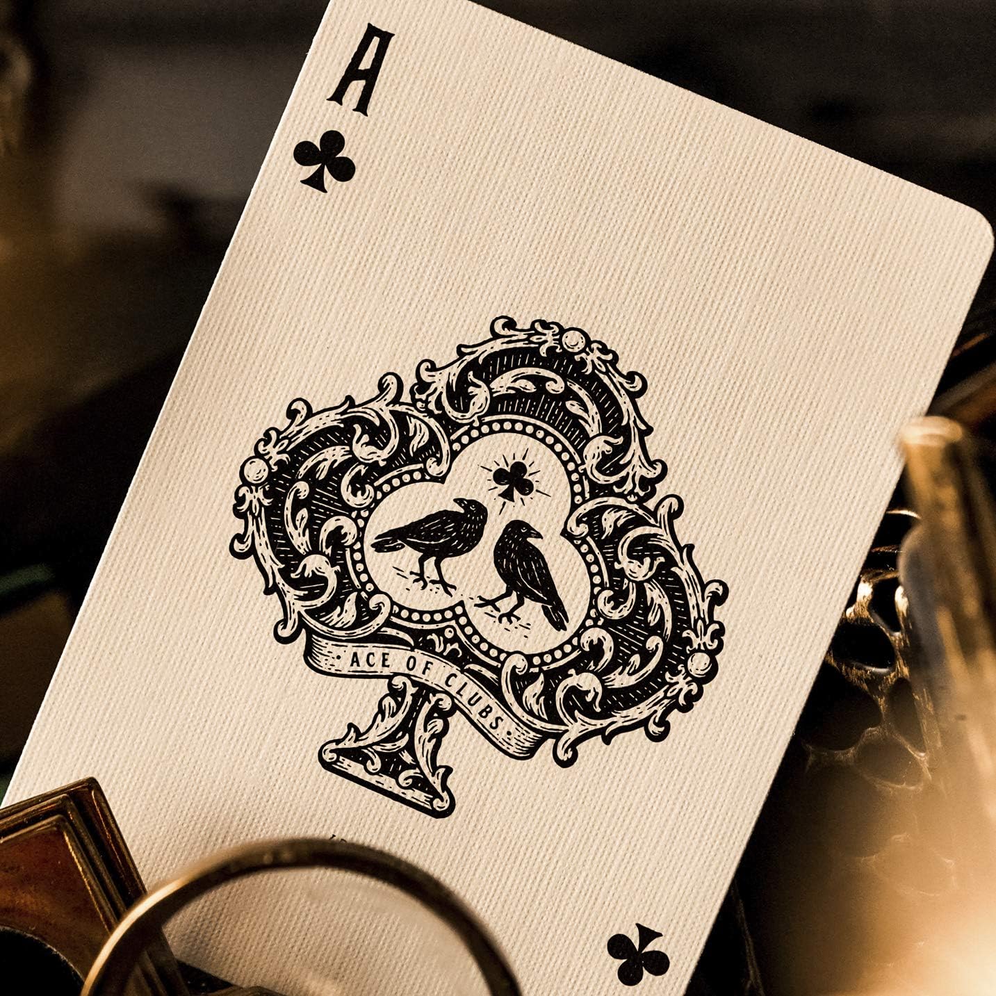 Wide shot of Ace of clubs card resting among brass props and vintage objects.