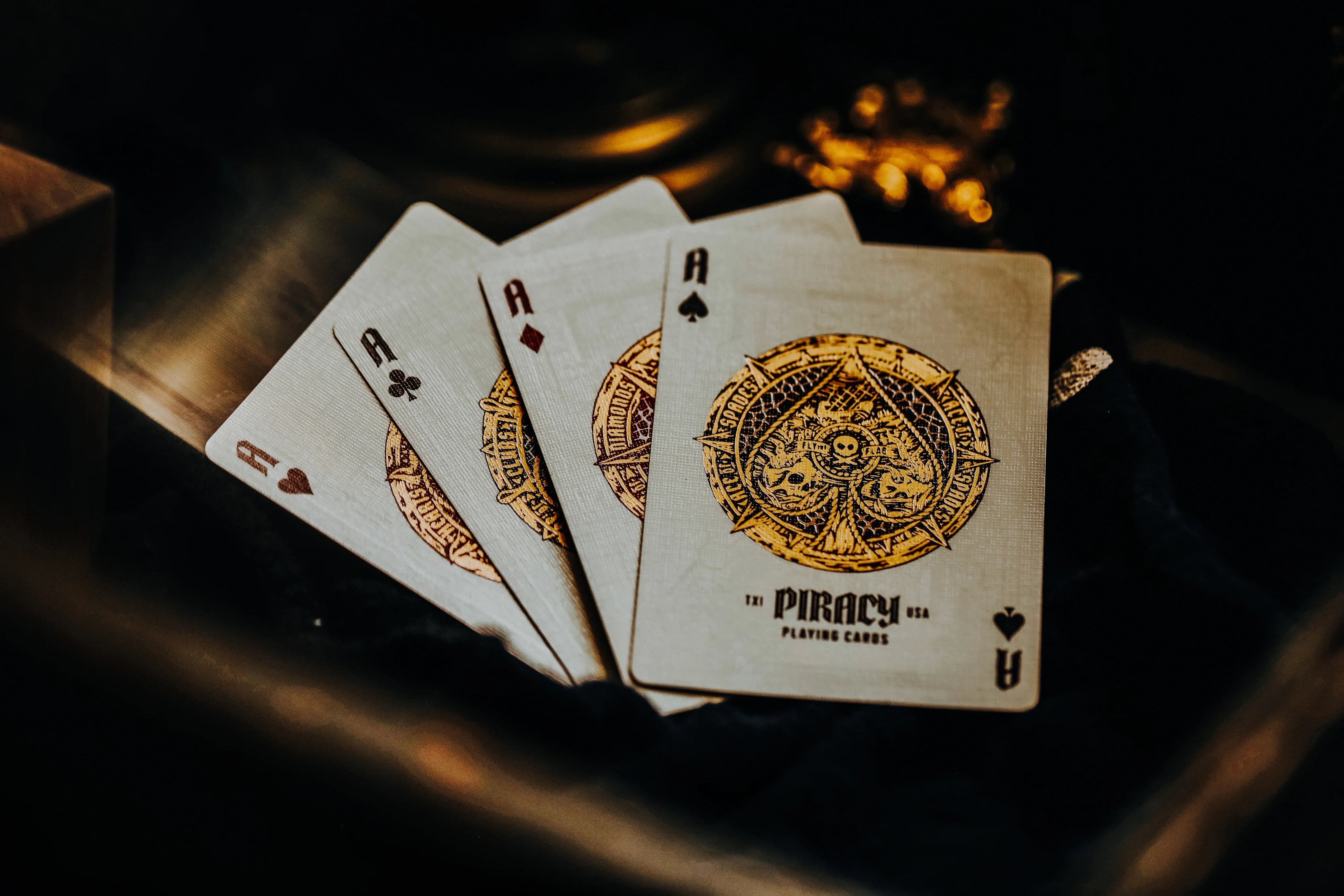 Four Piracy playing cards with a distinctive design on a dark background