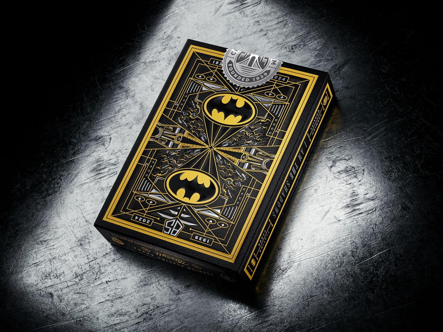 Batman-themed playing card box with gold accents on a dark textured surface