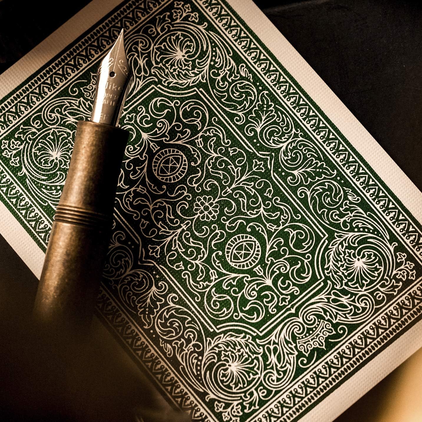 Close-up of Derren Brown card back showing green filigree pattern and circular emblems.
