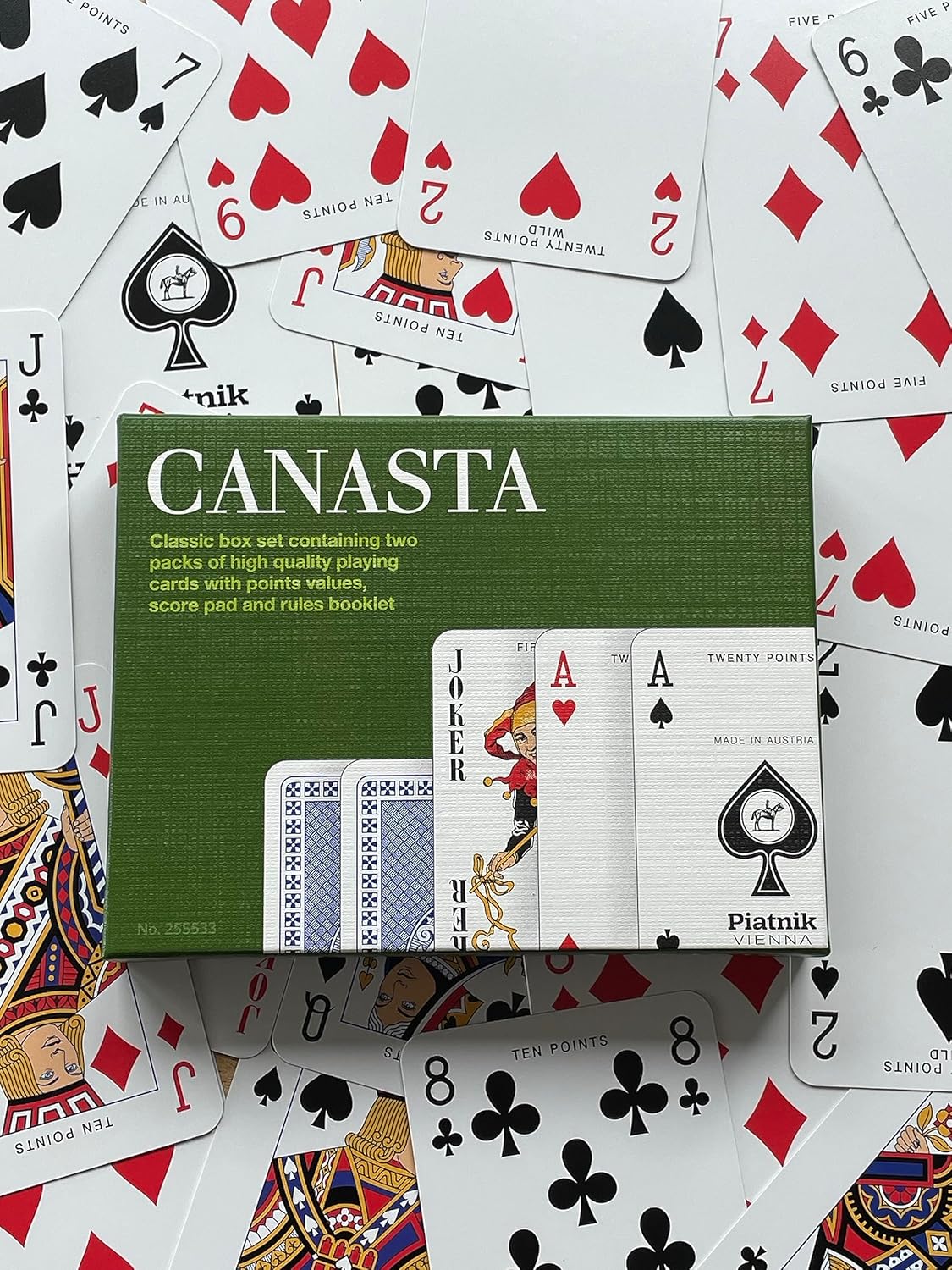 Canasta playing card set with green box and scattered cards on a white background