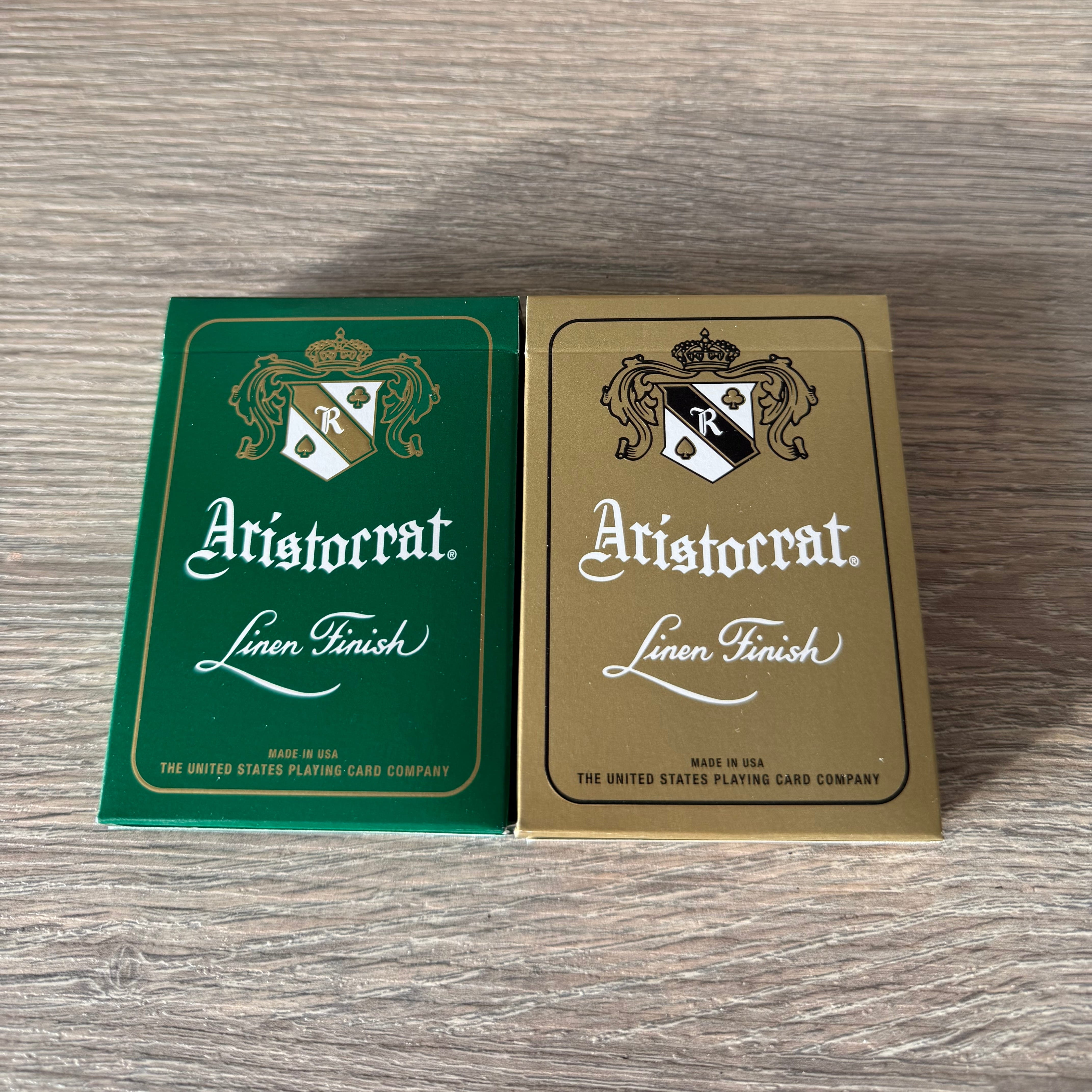 Aristocrat 727 Currency Green & Gold playing card decks side by side on a wood table