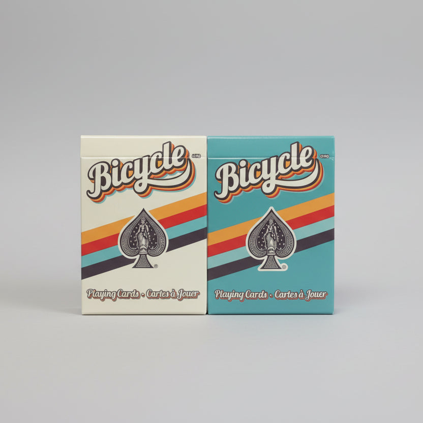Two boxes of Bicycle playing cards, one white and one blue, with colorful stripes and the Bicycle logo.