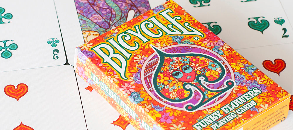 Front of Bicycle Funky Flower Playing Cards tuck box surrounded by cards with custom retro-style suits
