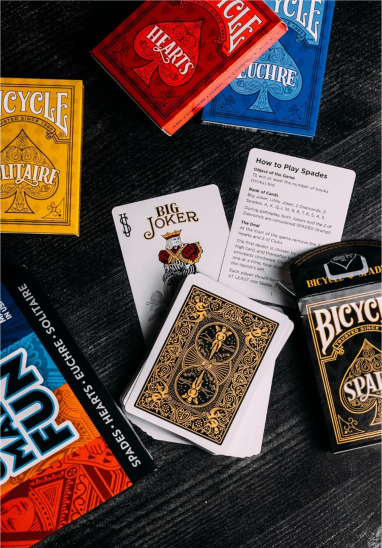 Collection of Bicycle playing cards in various colors on a dark surface.