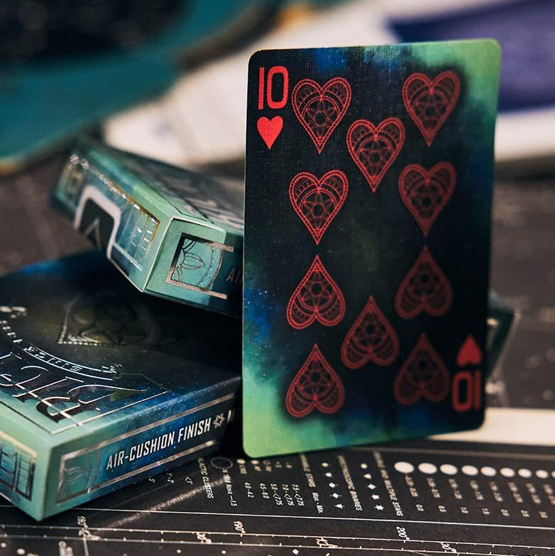 Playing card with red hearts design on a black surface with a teal box.