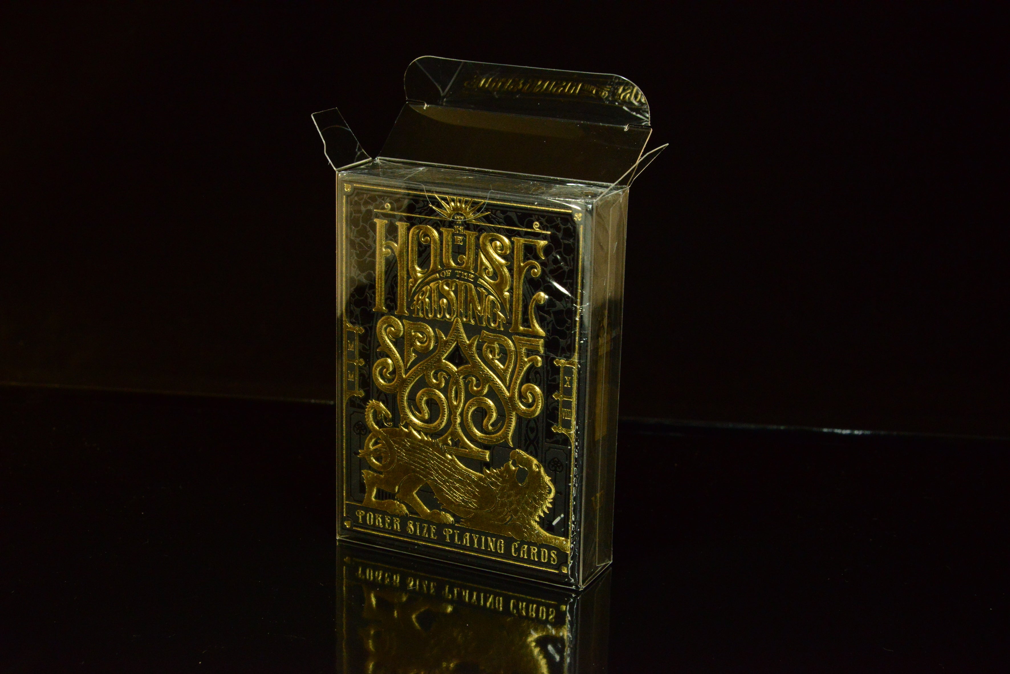 Gold playing card box with intricate design on a black background