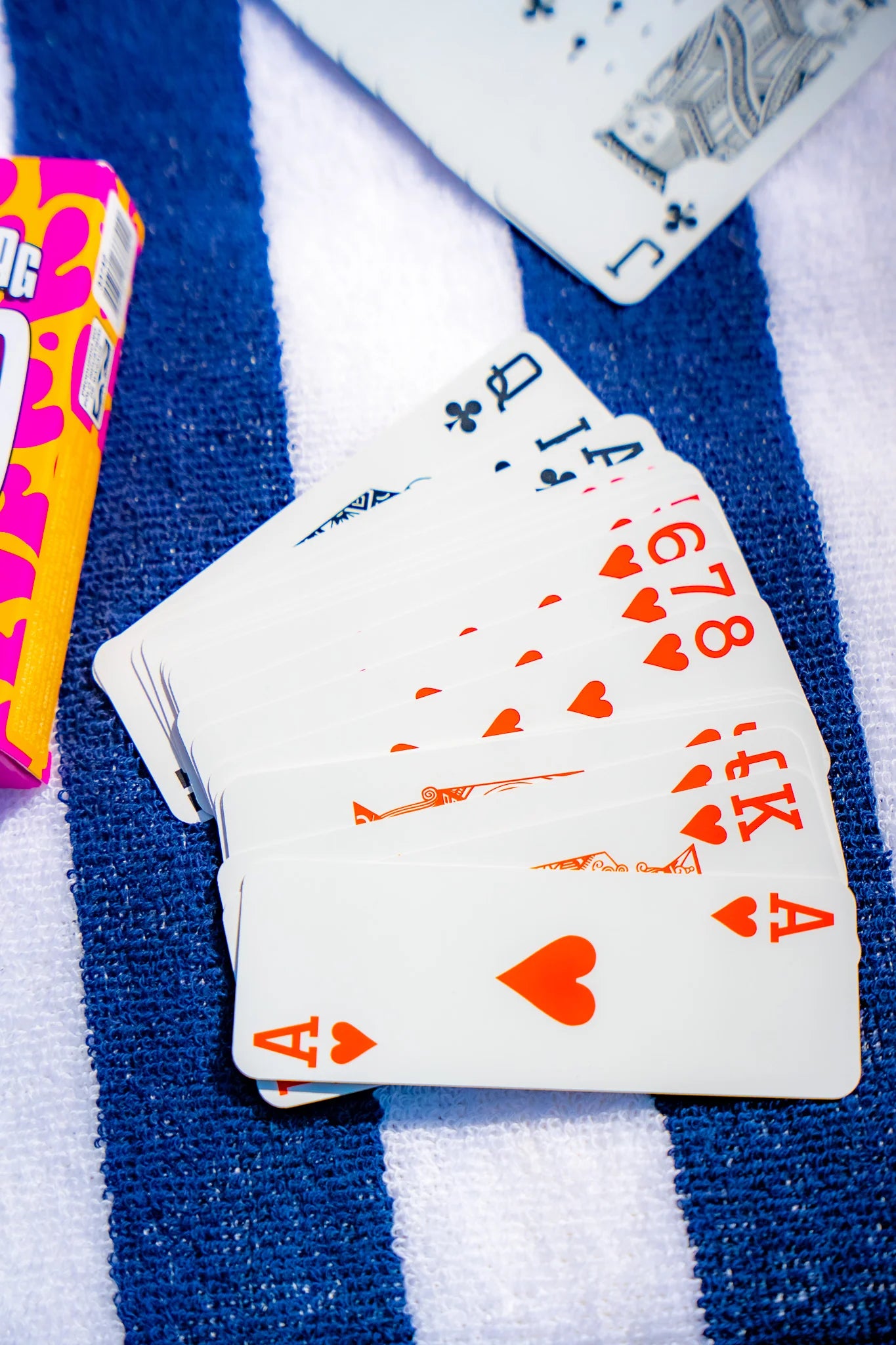 Copag Go Deck – Tiger Design Playing cards on a blue and white striped surface with a colorful box in the background.