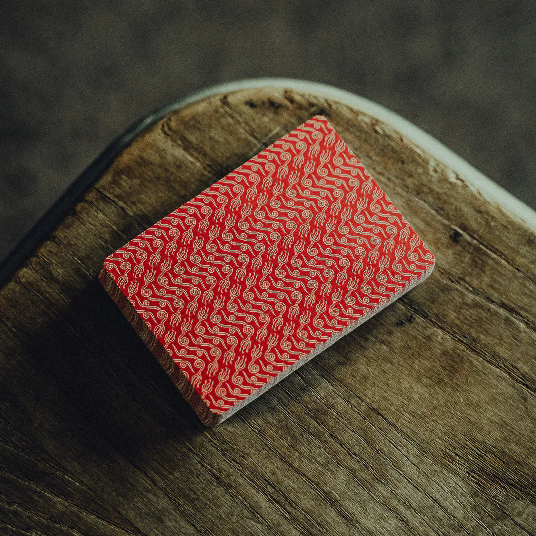 NO BORDERS: Series 2 Playing Cards Red crown patterned card on a wooden surface with a dark background