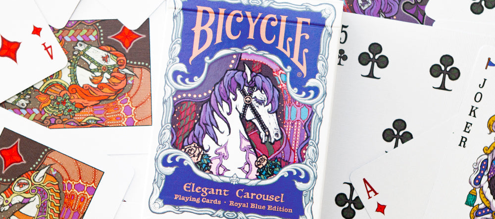 Bicycle Elegant Carousel Royal Blue Edition tuck box displayed on a spread of custom playing cards
