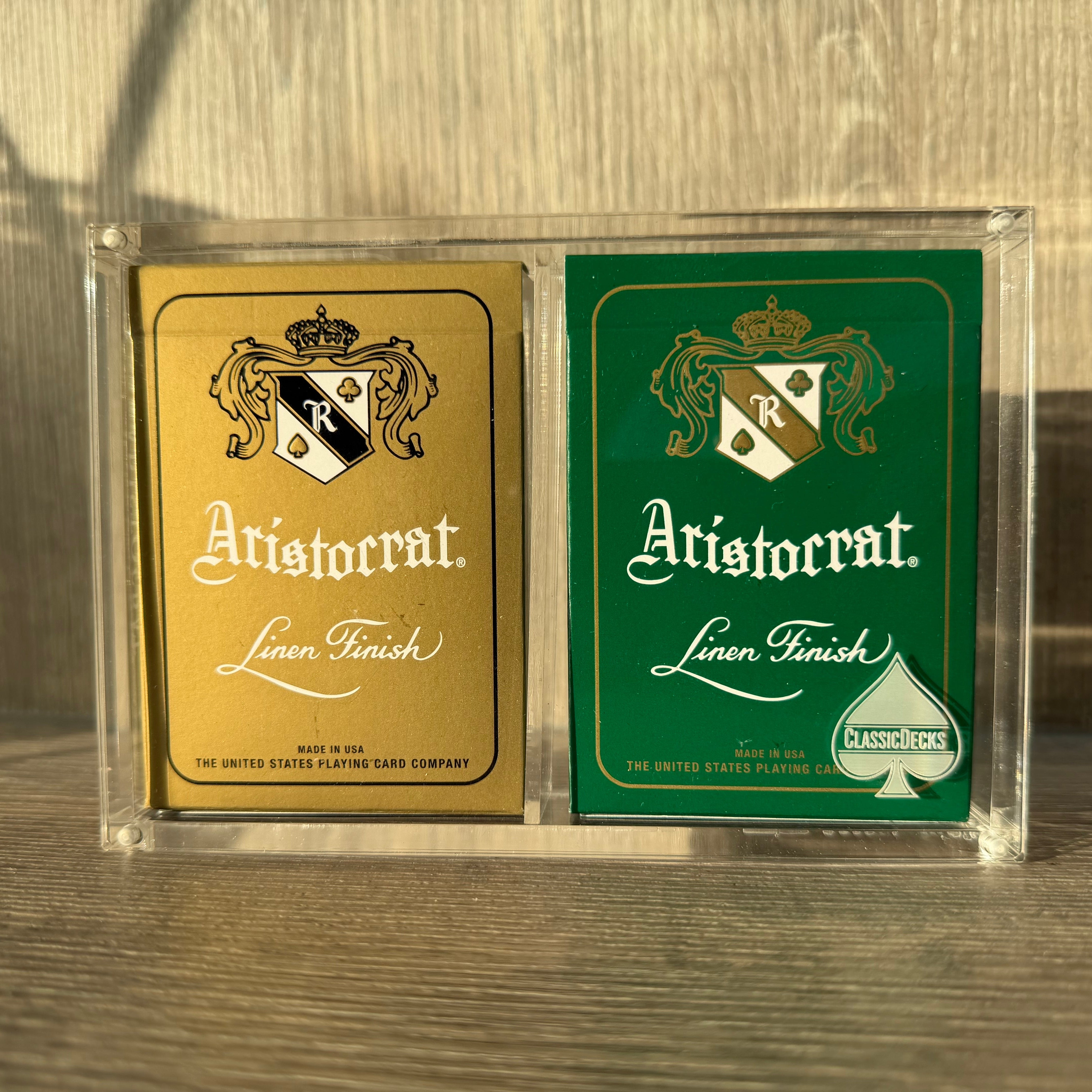 Aristocrat 727 Currency Green & Gold playing card decks in X2 case on a wood table