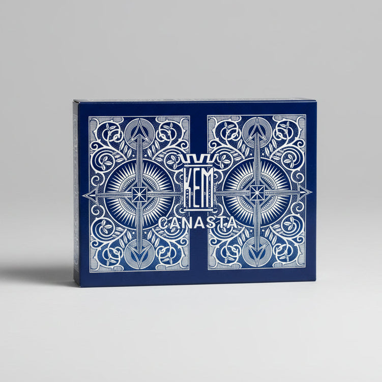Blue and white KEM playing card box with intricate designs on a gray background