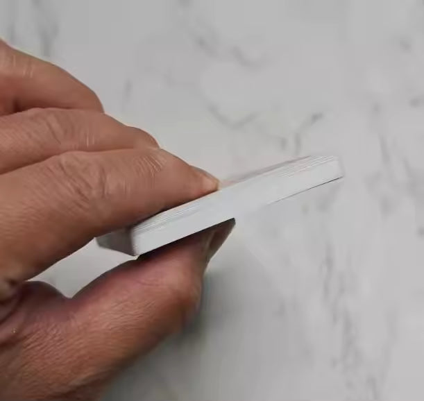 Hand holding a white rectangular object against a light gray background