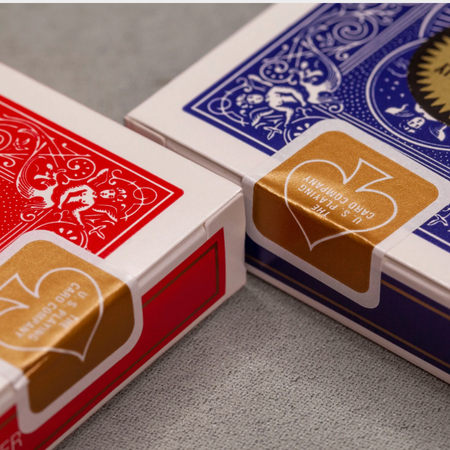 Two decks of playing cards, one red and one blue, on a gray surface.
