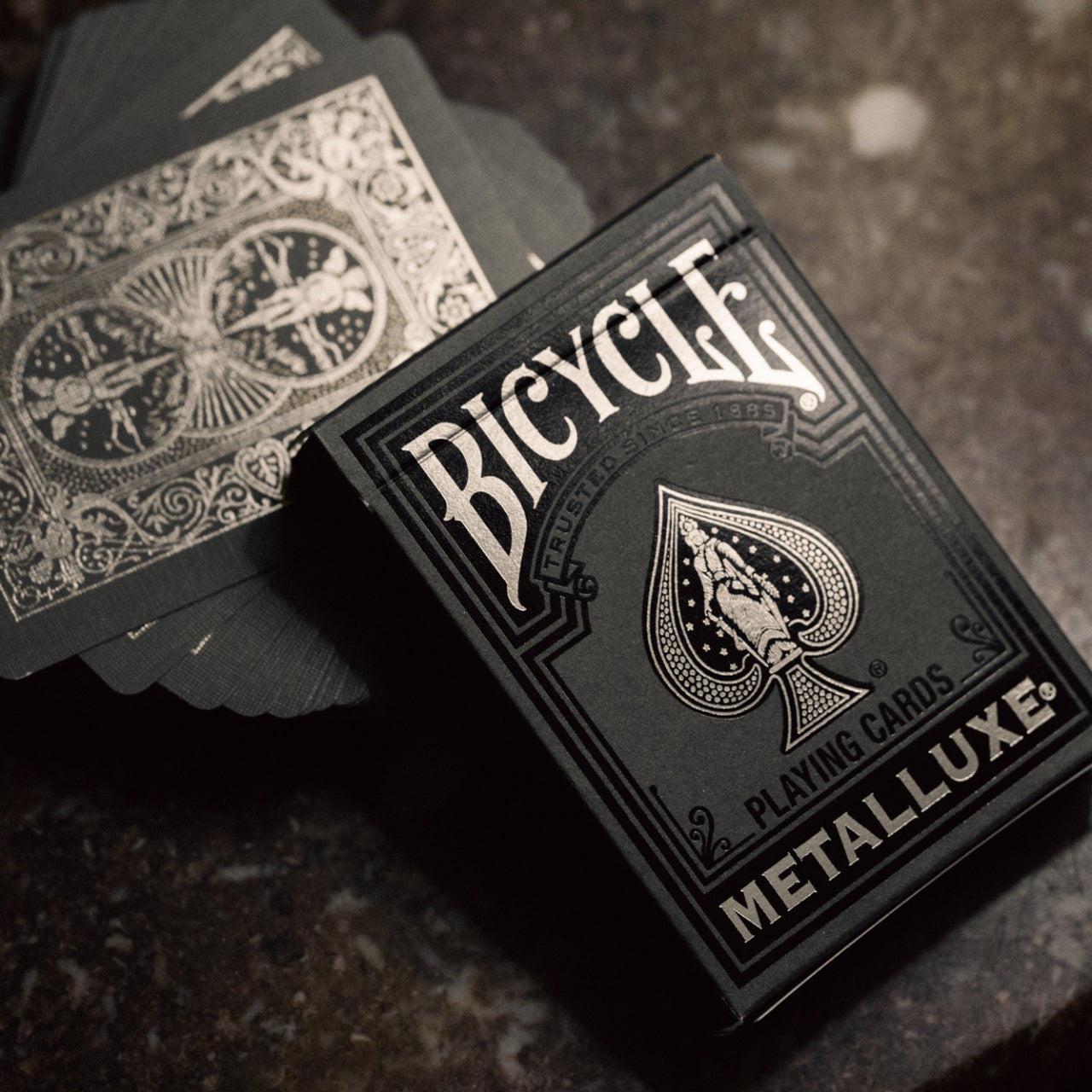 Bicycle Black & Silver Metalluxe playing cards on a dark textured surface