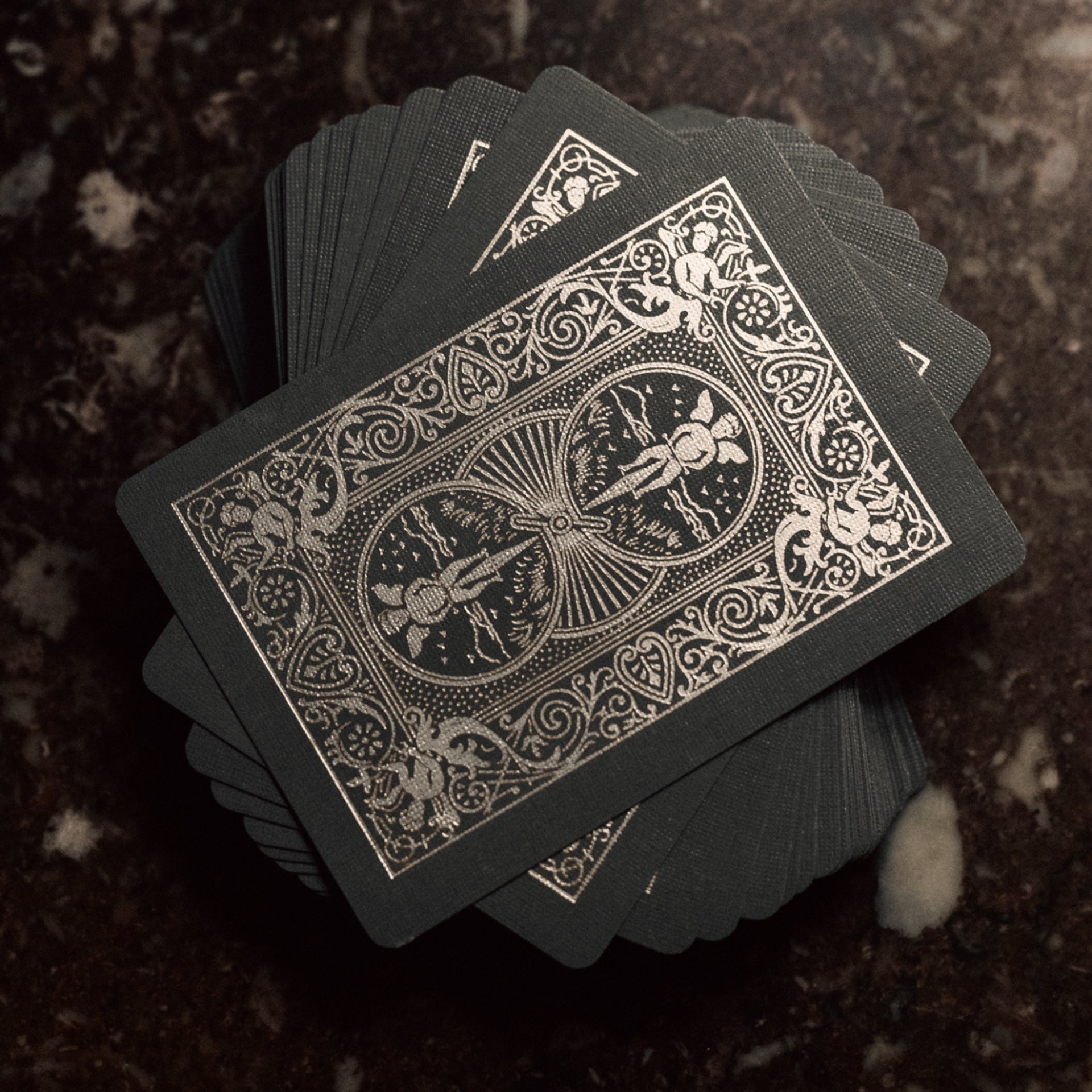 Bicycle Black & Silver Metalluxe playing cards with gold intricate designs on a dark textured surface