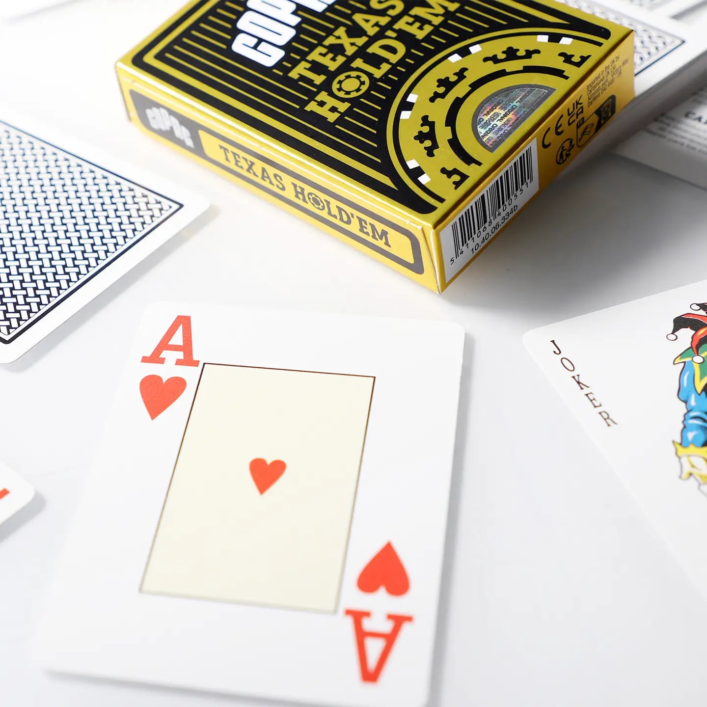 Playing cards with an Ace of Hearts and a Texas Hold'em card box on a white surface.