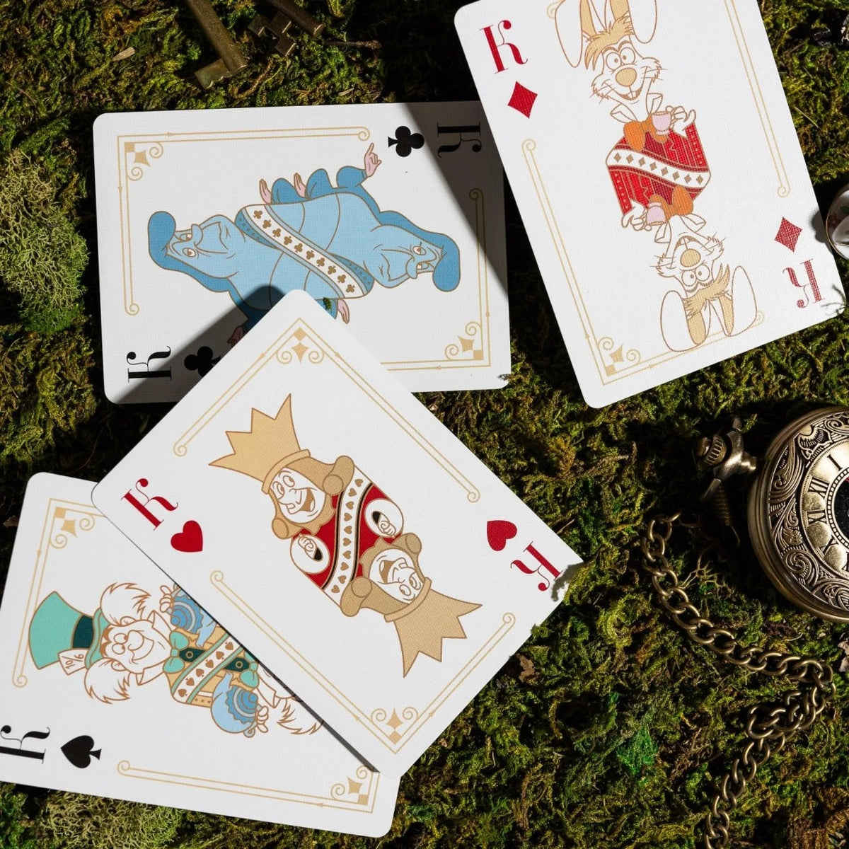 Bicycle Alice in Wonderland court cards featuring the Caterpillar and royal characters arranged on moss beside a pocket watch.