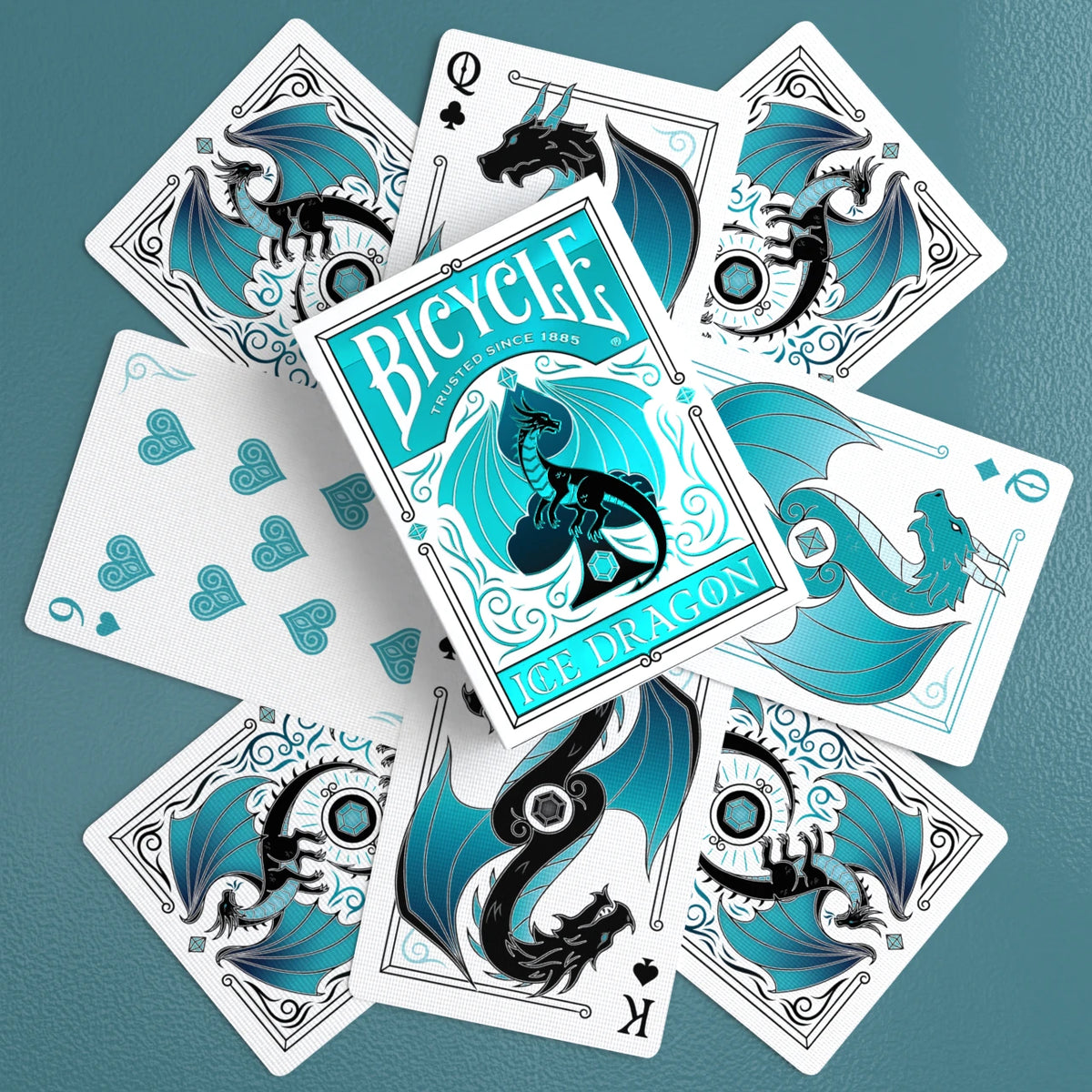 Bicycle Ice Dragon foil tuck box centered over dragon courts, number cards, and card backs on a teal surface