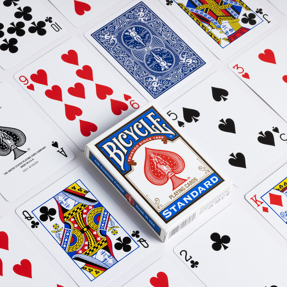 Blue Bicycle Standard tuck box surrounded by traditional court cards, the Ace of Spades, number cards, and a blue Rider Back.