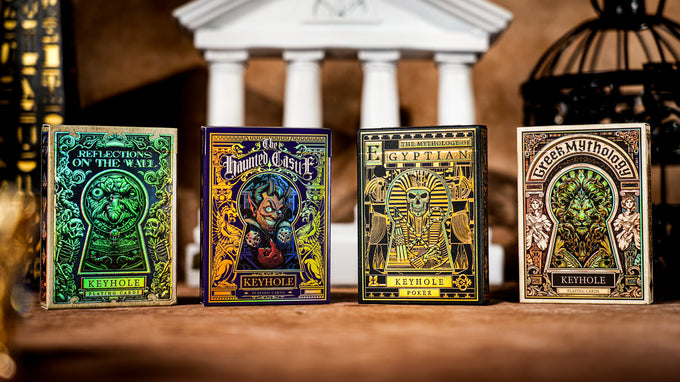 Four Keyhole Luxury Edition playing card decks with decorative covers on a wooden surface.