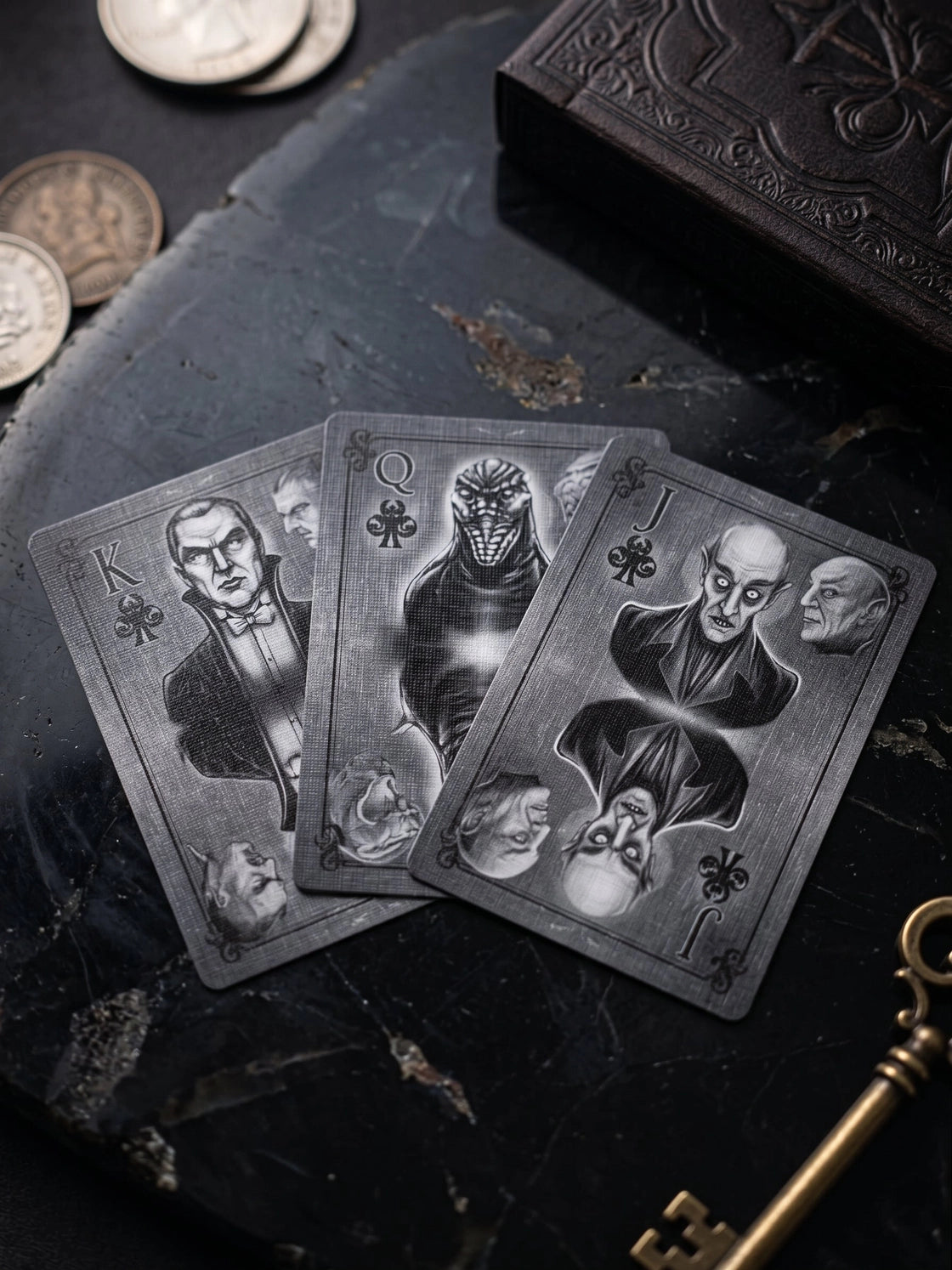Classic Monsters Playing Cards King, Queen, and Jack of clubs with grayscale monster portraits beside coins and an antique key