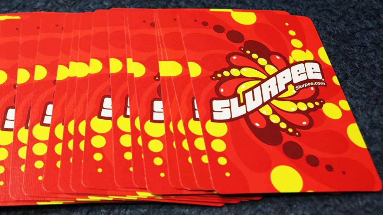 Red cards with Slurpee logo and yellow polka dots on a dark surface