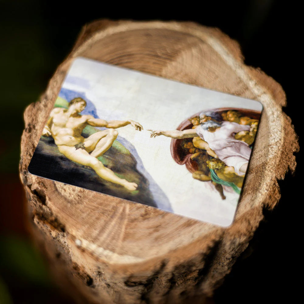 Close-up of a wooden block with a printed image of 'The Creation of Adam' on it.