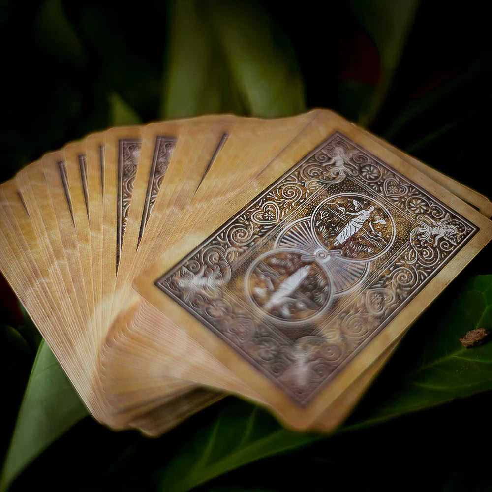 Fanned-out deck of playing cards with intricate designs on a green leaf background