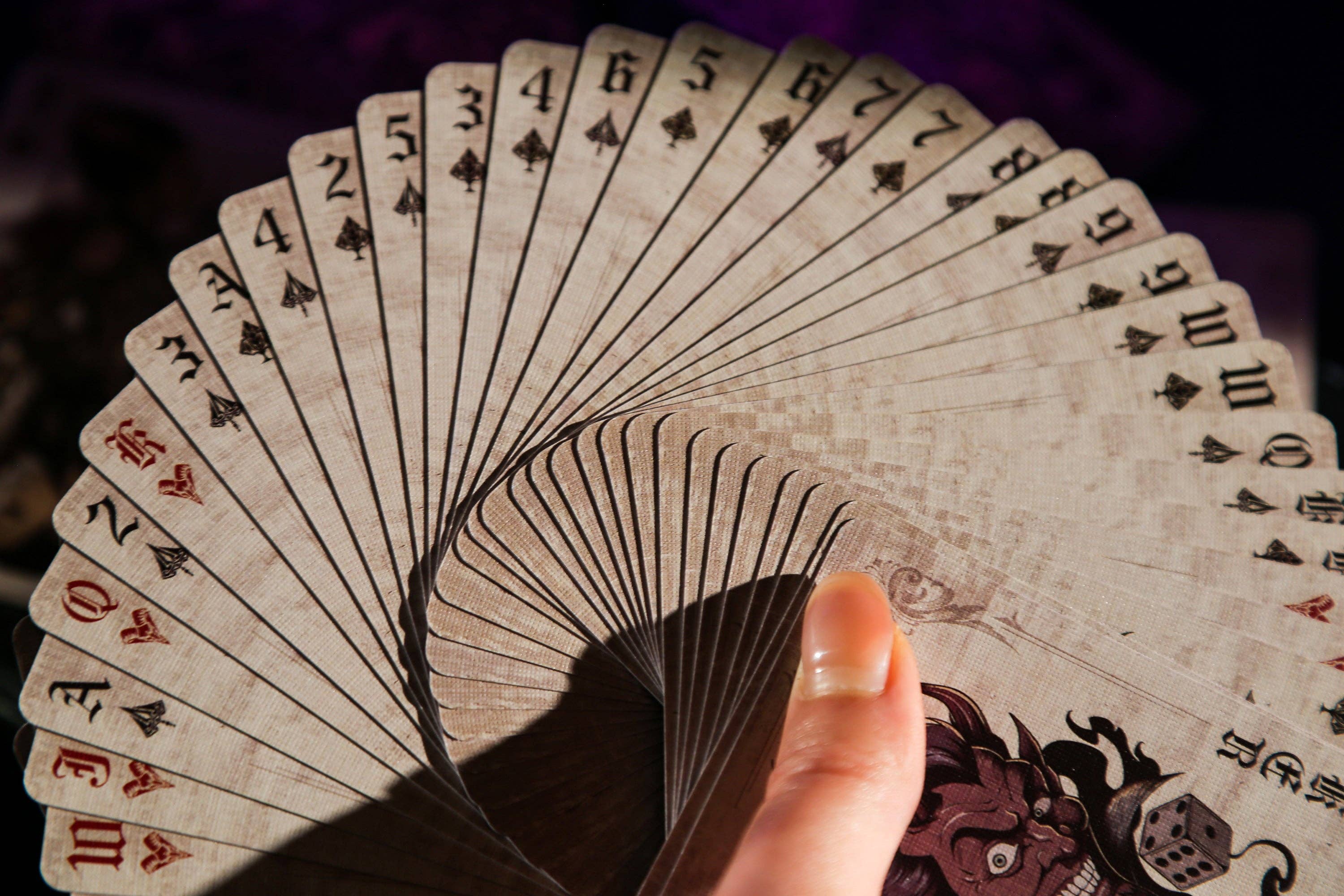 Fanned-out deck of playing cards held by a hand against a dark background