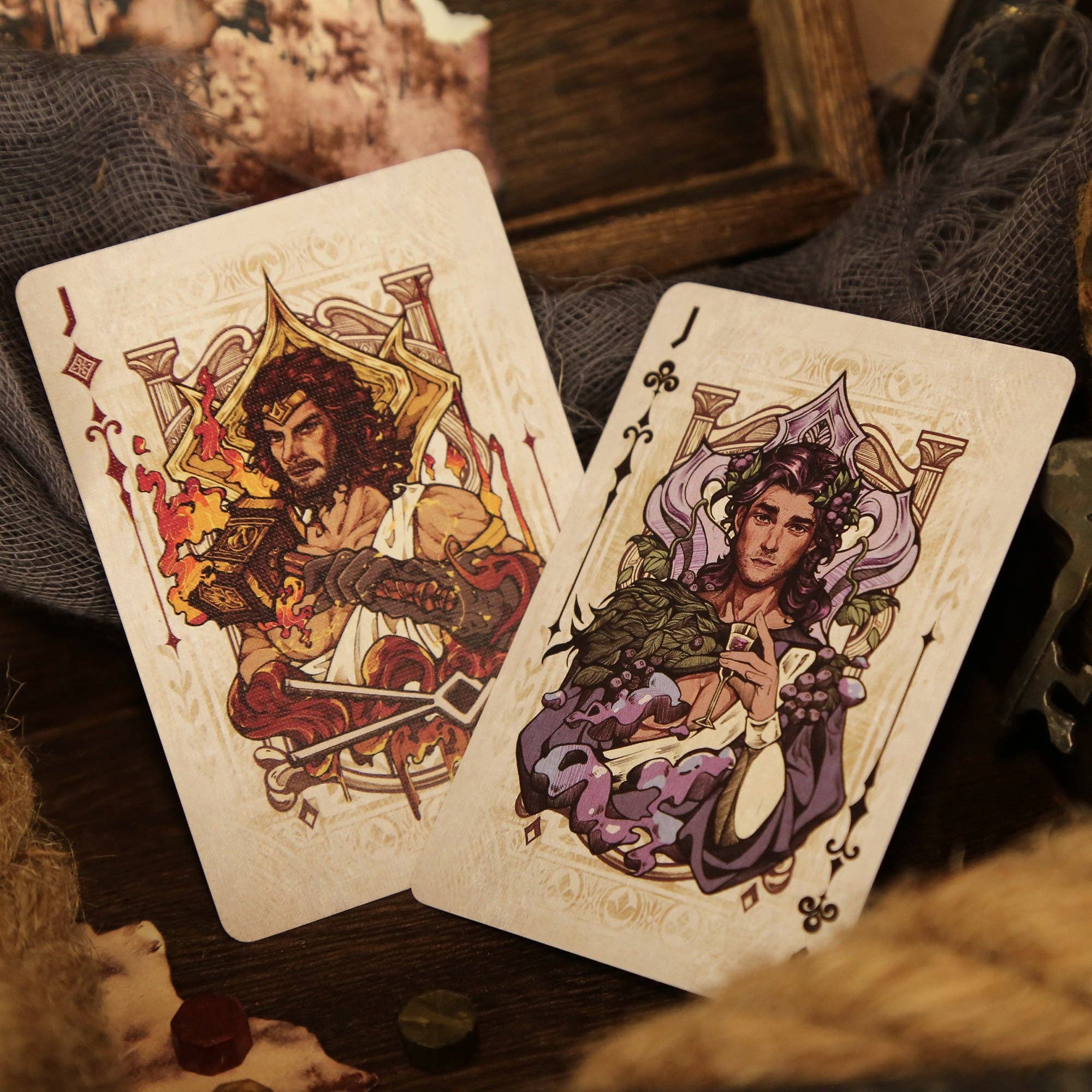 Two playing cards with artistic illustrations of characters on a textured surface.