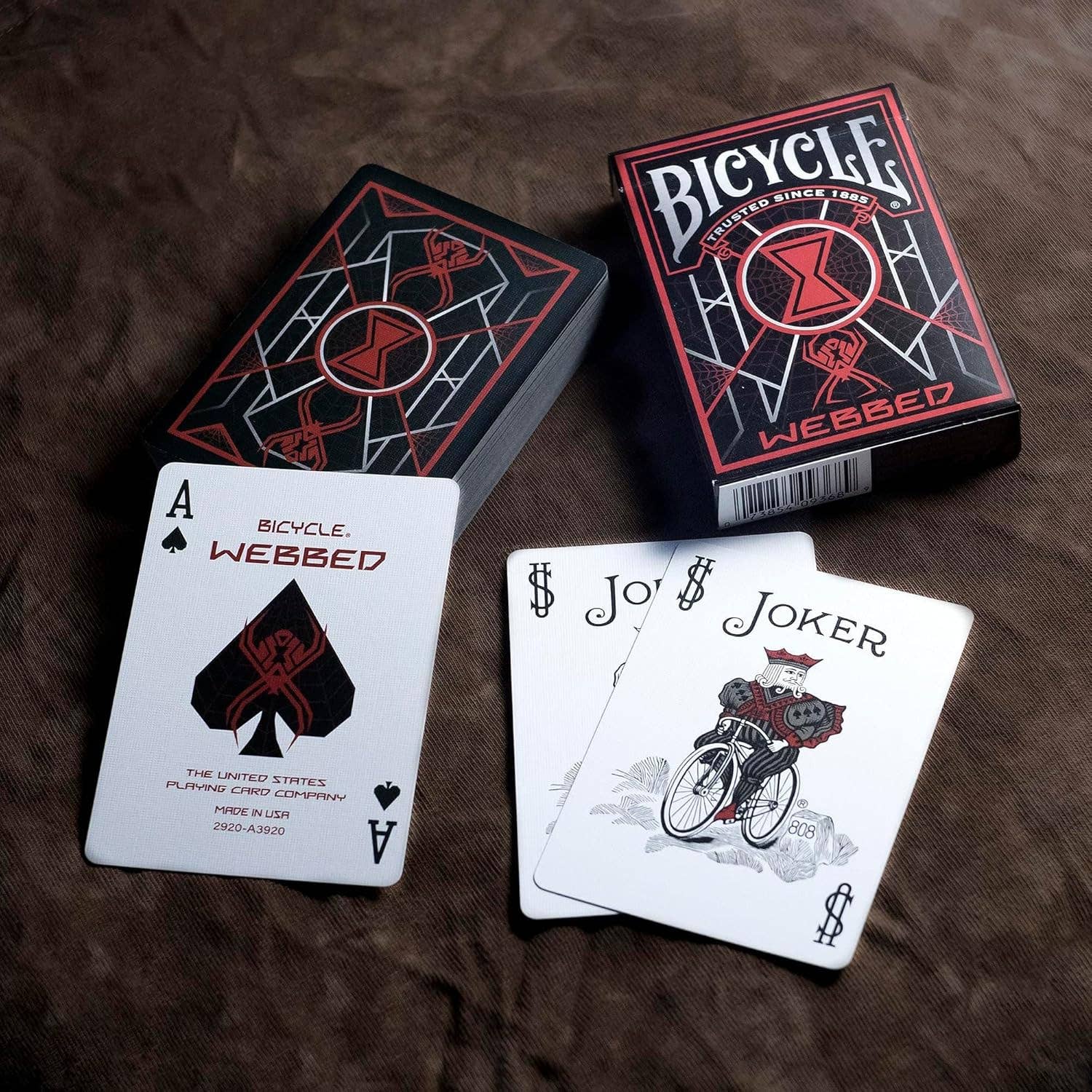 Bicycle Webbed playing cards with an Ace of Spades and Joker card on a brown surface