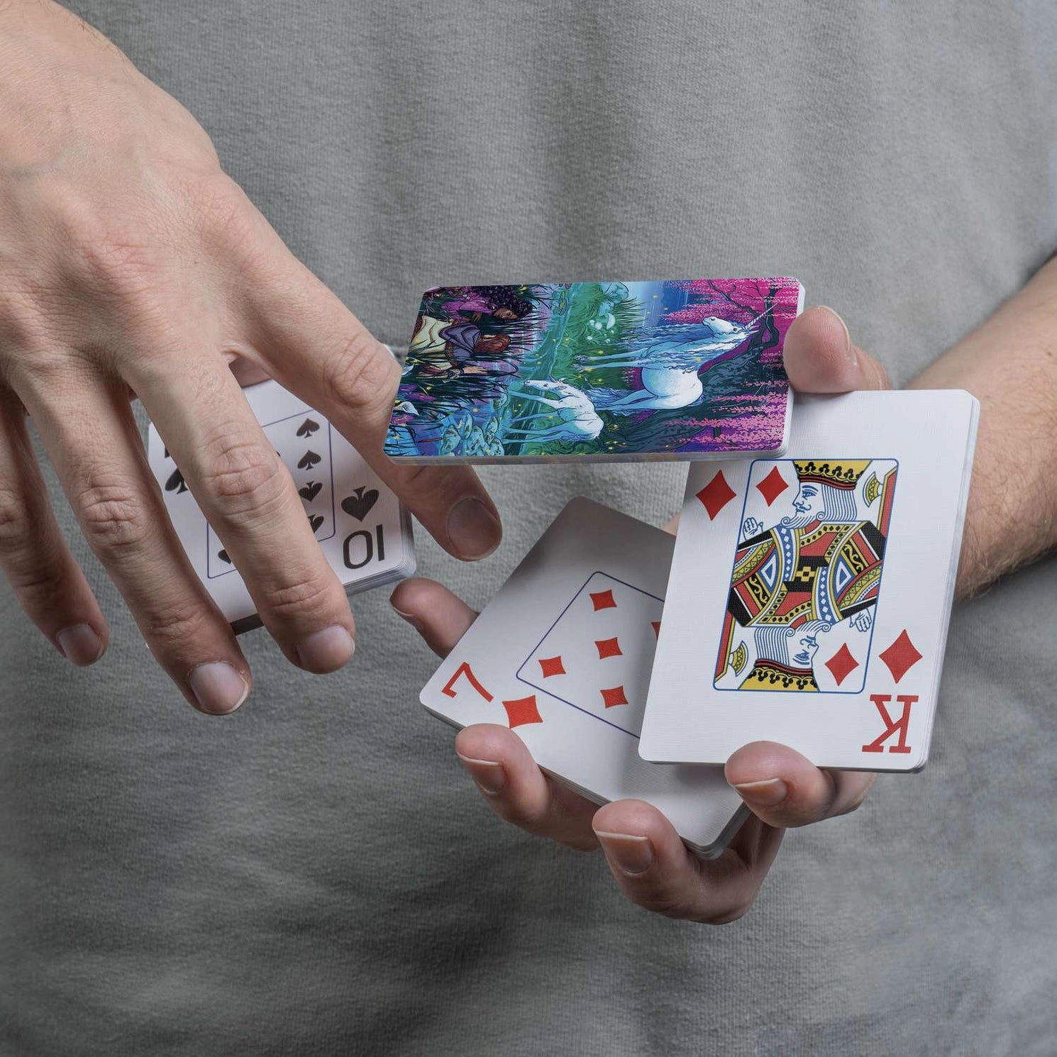 Finding Unicorns scenic card back displayed during a flourish with traditional playing-card faces
